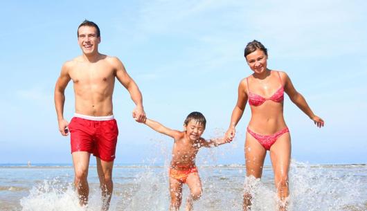Famiglia felice corre in acqua al mare.