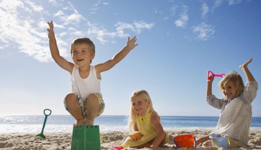 Bambini giocano felici sulla spiaggia con secchielli e pale.