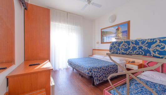 Camera con letti a castello, TV e ventilatore a soffitto.