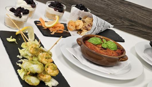Piatti gourmet con dolci, spiedini e una casseruola.