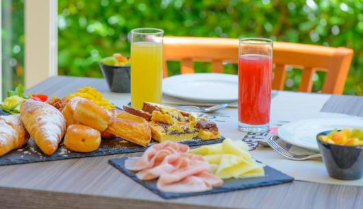 Colazione con dolci, salumi e succhi freschi su un tavolo.