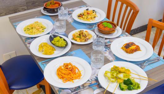 Tavola imbandita con piatti di pasta e verdure.