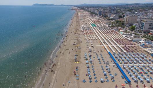 Spiaggia affollata con ombrelloni e mare cristallino.