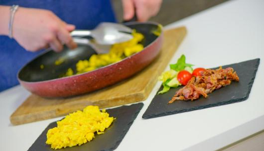 Uova strapazzate e pancetta su piatti di ardesia.