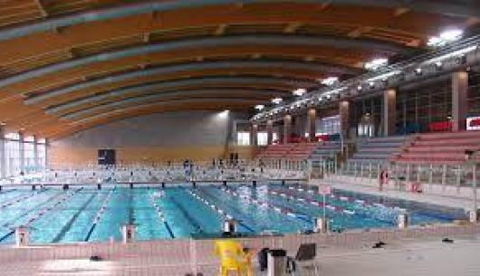 Piscina coperta con corsie e gradinate per spettatori.